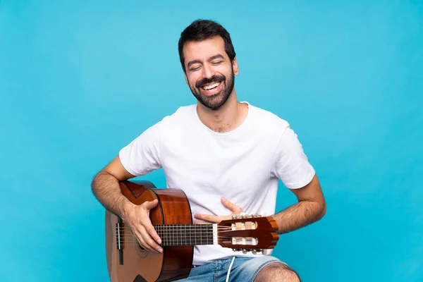 Jongeman Met Gitaar Geïsoleerde Blauwe Achtergrond Glimlachen Veel — Stockfoto