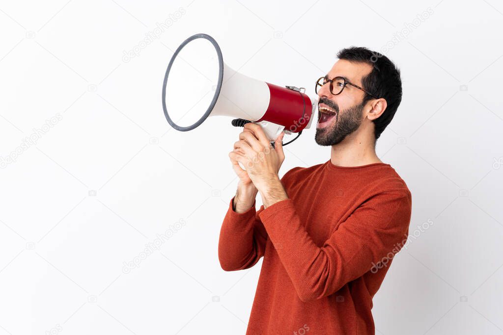 Caucasian handsome man with beard over isolated white background shouting through a megaphone