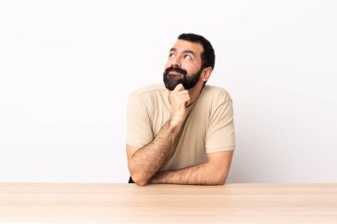 Masada sakallı beyaz bir adam yukarı bakarken bir fikir düşünüyor..