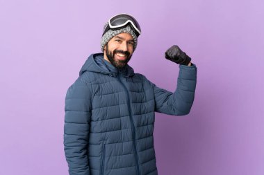 Kayak gözlüklü kayakçı mor arka planda güçlü bir jest yapıyor.