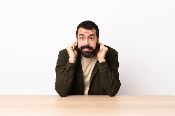 Caucasian Man Beard Table Frustrated Covering Ears — Stock Photo, Image