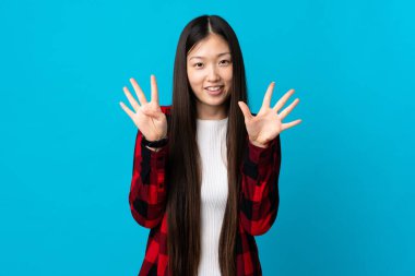 İzole edilmiş mavi arka plan üzerinde genç Çinli kız parmaklarıyla dokuz sayıyor.