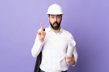 Miğferli genç bir mimar, elinde mor arkaplan üzerine planlar tutuyor. Çözümü bulmak için parmağını kaldırıyor.