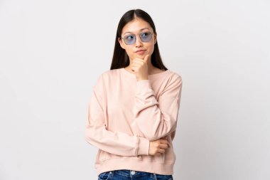 Genç Çinli kız, beyaz arka planda izole edilmiş bir şekilde bakarken bir fikir düşünüyor.