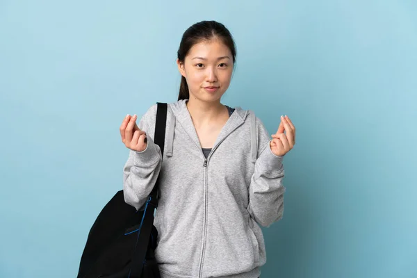 年轻的中国女子 身披运动包 身披深蓝色背景 做着赚钱的姿势 — 图库照片