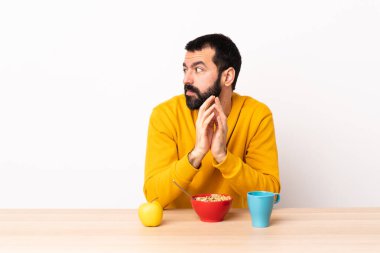 Kafkasyalı bir adam kahvaltı yapıyor, masa başında bir şeyler planlıyor..