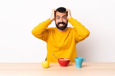 Beyaz bir adam masada kahvaltı yapıyor. Gergin hareketler yapıyor..