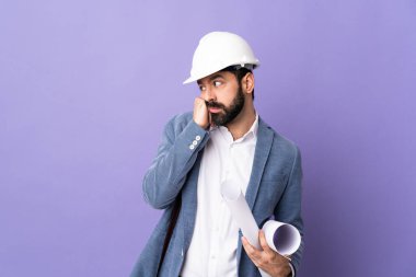 Miğferli genç bir mimar, elinde yorgun ve sıkılmış bir ifadeyle izole edilmiş mor arka plan planları tutuyor.