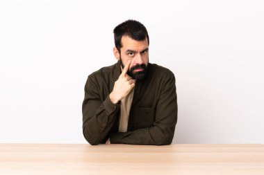 Masada sakallı beyaz bir adam bir şey gösteriyor..