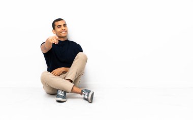 Yerde oturan Afro-Amerikalı adam kendinden emin bir ifadeyle seni işaret ediyor.