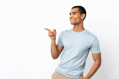 İzole edilmiş beyaz arka planda yaşayan Afro-Amerikalı bir adam parmağını yana uzatıp bir ürün sunuyor.