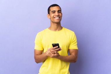 Cep telefonu alkışlarıyla izole edilmiş mor arka plan üzerinde Afrikalı Amerikalı bir adam.