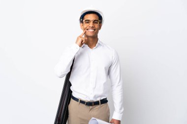 Kafasında miğferi olan ve izole edilmiş beyaz arkaplan üzerinde planları olan Afrikalı Amerikalı mimar mutlu ve hoş bir ifadeyle gülümsüyor.