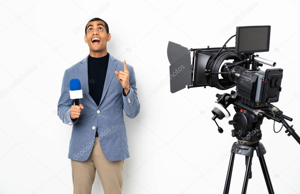 Reporter African American man holding a microphone and reporting news over isolated white background pointing up and surprised