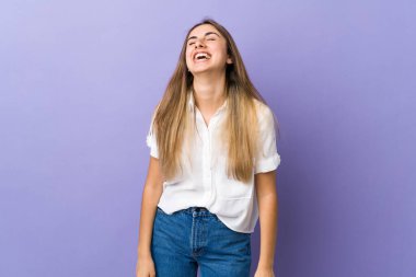 Mor arka planda yaşayan genç bir kadın gülüyor.