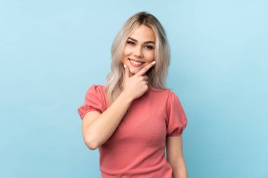 Izole mavi arka plan üzerinde genç kız gülümseyerek