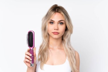 Genç sarışın kız izole edilmiş beyaz arka plan ve saç tarağı.