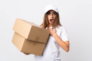 Soyutlanmış beyaz arka planda genç teslimatçı kadın sağa bakarken şaşırmış ve şok olmuştu.