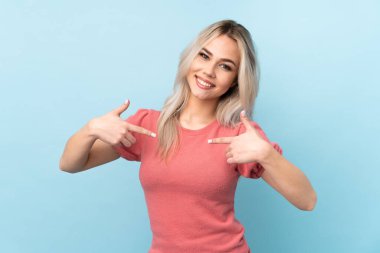 Genç kız soyutlanmış mavi arka planda gururlu ve kendini beğenmiş.