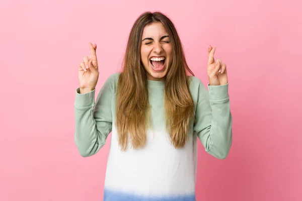 Jovem Mulher Sobre Fundo Rosa Isolado Com Dedos Cruzando — Fotografia de Stock