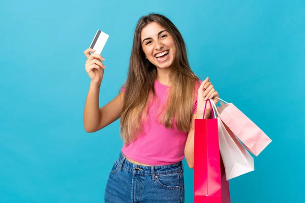 Soyutlanmış Mavi Arka Planda Genç Bir Kadın Elinde Alışveriş Çantaları — Stok fotoğraf