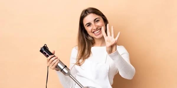 Mulher Usando Liquidificador Mão Sobre Fundo Isolado Feliz Contando Quatro — Fotografia de Stock