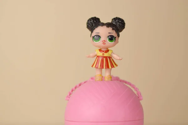На столі лежить кольорова пластикова лялька і контейнер для іграшок. Lol Surprise series Toys produced by Mga Entertainment inc. — стокове фото