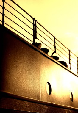 Slightly silhouetted view of a reconstructed section of the R.M.S. TITANIC's hull with visible portholes and attached fairlead. clipart