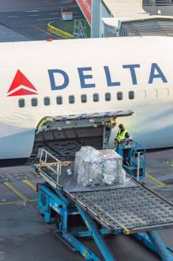 Hollanda, Schiphol Havaalanı 'ndaki bir Delta Havayolları uçağına bir kargo konteynırı yüklemek.