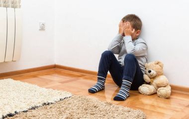 Üzgün çocuk yüzünde elleriyle katta oturan