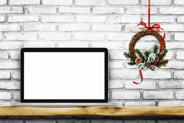 Blank screen laptop on white brick wall with Christmas wreath — Stock Photo, Image