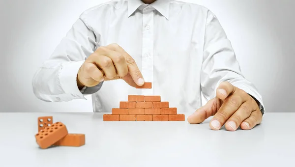 Businessman hand placing a brick on a wall — Stock Photo, Image