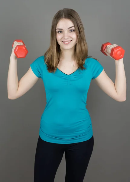 Chica con dumpbells en gris fondo deporte concepto gimnasio — Foto de Stock