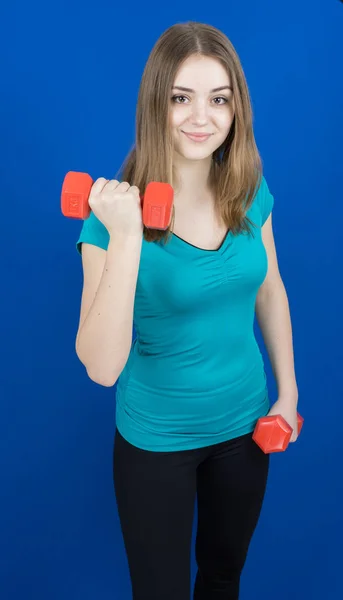 파란색 배경 스포츠 개념 체육관에 dumpbells와 소녀 — 스톡 사진