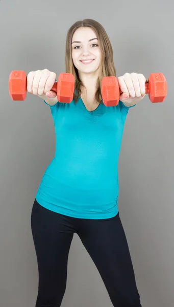 Menina com halteres no fundo cinza esporte conceito ginásio — Fotografia de Stock