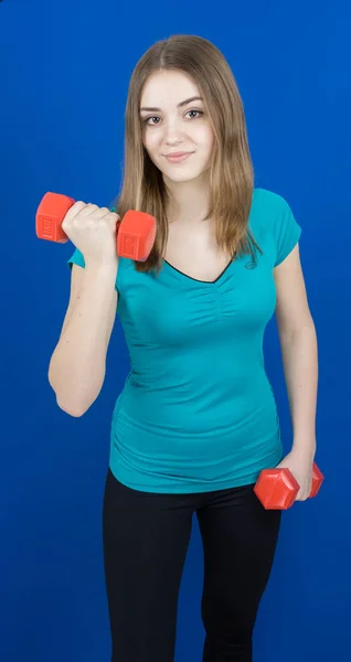 Girl with dumpbells on blue background sport concept gym — Stock Photo, Image