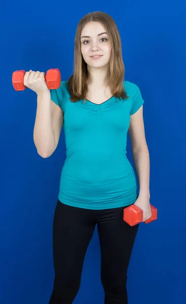 Girl with dumpbells on blue background sport concept gym — Stock Photo, Image