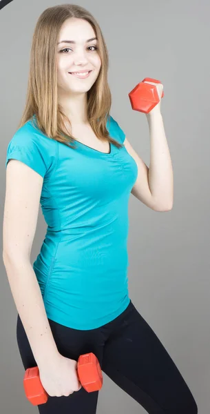 Girl with dumpbells on grey background sport concept gym — Stock Photo, Image