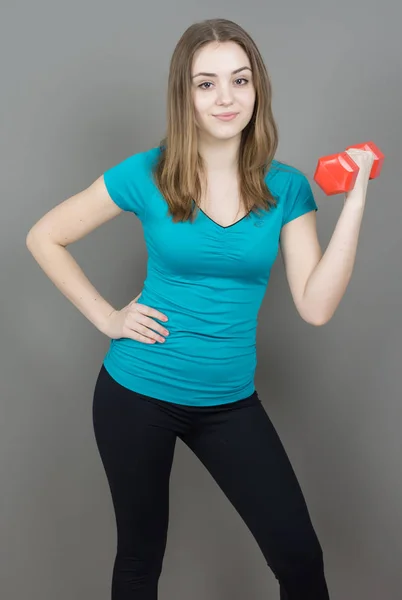 Girl with dumpbells on grey background sport concept gym — Stock Photo, Image