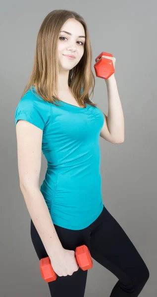 Girl with dumpbells on grey background sport concept gym — Stock Photo, Image