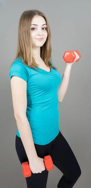 Dziewczyna z dumpbells na szarym tle sport concept siłowni — Zdjęcie stockowe