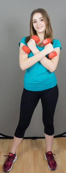 Girl with dumpbells on grey background sport concept gym — Stock Photo, Image