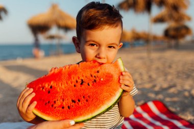Küçük çocuk karpuz yiyor.