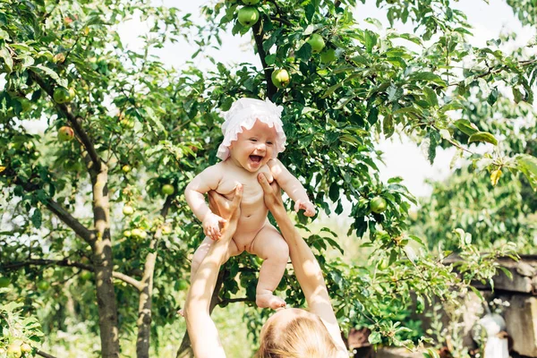 Kleine Mädchen und ihre Mutter sonnen sich im Garten. Apfelbaum. Sommer. Lächelnd. — Stockfoto