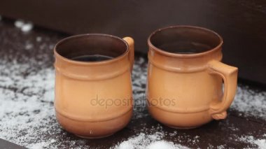 Karlı kış sabahı açık üzerinde dumanı tüten fincan sıcak kahve veya çay duran