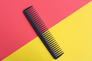 İki renkli arkaplanın ortasında siyah saç tarağı. Üst Manzara. Boşluğu kopyala.
