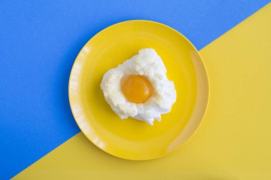Buluttaki yumurta iki renkli arka planda, sarı plakanın içinde. Üst Manzara. Boşluğu kopyala.