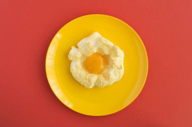 Kırmızı arkaplanın ortasındaki sarı plakalı buluttaki yumurta. Üst Manzara. Boşluğu kopyala.