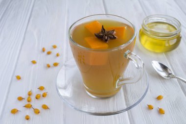 Balkabaklı çay, deniz dikenli karabatak ve beyaz ahşap arka plandaki cam bardakta baharat. Yakın çekim..