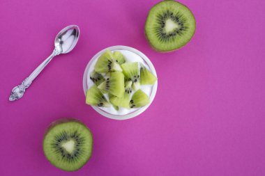 Pembe arka planda cam kavanozda kivi bulunan doğal süt yoğurdu. Uzayı kopyala Üst görünüm.